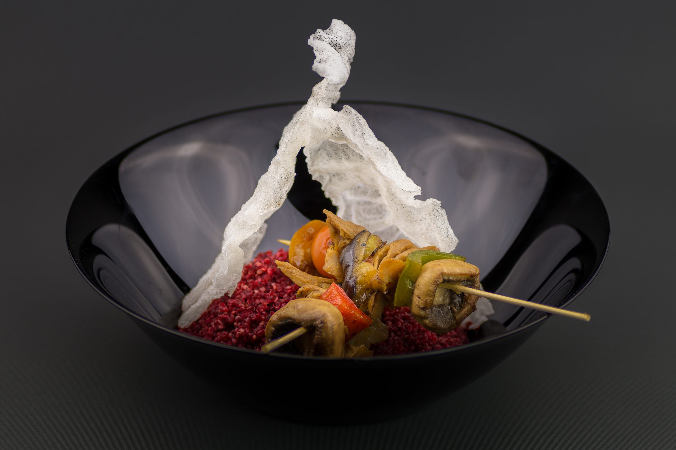 Brochetas de verdura sobre nido de quinoa roja